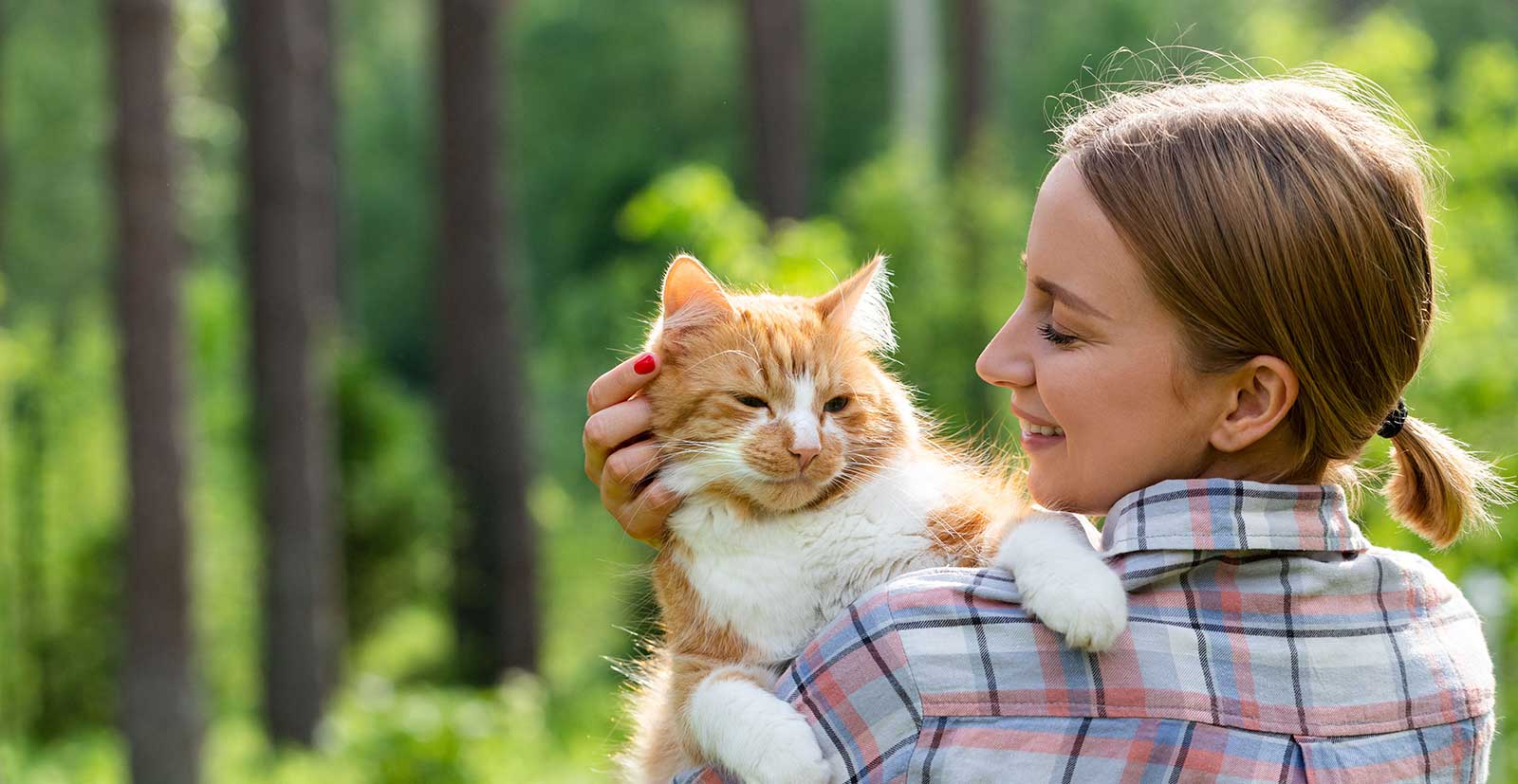 A woman holding a ginger cat outdoors
